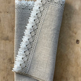 Nekrāsota, dabīgi pelēka toņa mīkstināta lina galda salvete ar divkrāsainu greznu lina mežģīni