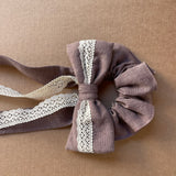 Lina auduma matu gumija - scrunchie - ar dekoratīvu banti Šokolādes lavandas tonis, ar mežģīni