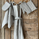 Gaiši zilas/dabīgi pelēkas svītriņas (~2.5mm), viegli mīkstināta lina auduma priekšauts ar kabatiņu un regulējamām lencēm