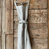 Gaiši zilas/dabīgi pelēkas svītriņas (~2.5mm), viegli mīkstināta lina auduma priekšauts ar kabatiņu un regulējamām lencēm