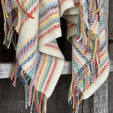 Krāsainas svītriņas uz piena balta fona aitas vilnas pleds ar bārkstīm