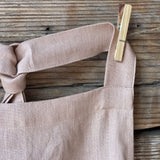 Maigi rozā toņa lina auduma priekšauts ar kabatiņu un regulējamām lencēm