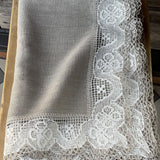 Nekrāsota, dabīgi pelēka toņa lina galdauts ar ~6cm platu balti-pelēku lina mežģīni ar ziedu rakstu