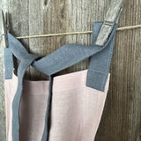 Maigi rozā toņa lina auduma priekšauts ar tumši pelēkām lencēm un kabatiņu