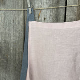 Maigi rozā toņa lina auduma priekšauts ar tumši pelēkām lencēm un kabatiņu