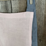 Maigi rozā toņa lina auduma priekšauts ar tumši pelēkām lencēm un kabatiņu